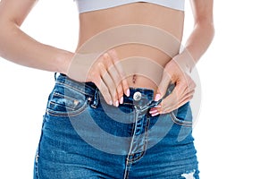 cropped view of girl with slim waist taking off jeans, isolated on white