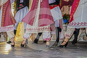 Cropped view of Greek dancers on stage in beautiful embroidered costume with women in front of men - legs and feet - movement blur