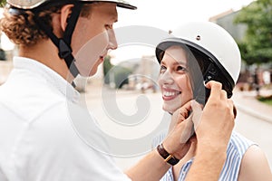 Cropped view of happy man fastens a helmet to girlfriend