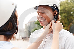 Cropped view of happy woman fastens a helmet to boyfriend