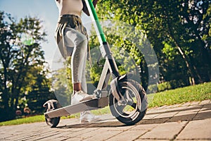 Cropped view of her she teenage teen trendy skinny slim fit hipster girl& x27;s legs riding kick scooter spending free time