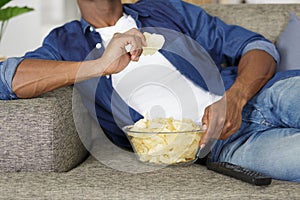 Cropped view man eating snacks while watching tv