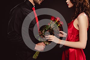 Cropped view of man giving bouquet of roses to elegant woman