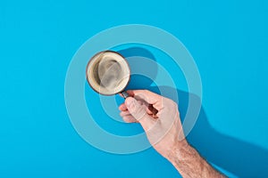 View of man holding cup of fresh coffee on blue background