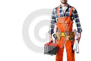 Cropped view of man in orange overall holding tool box and blueprint