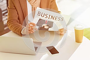 Cropped view of man reading business newspaper and sitting at table