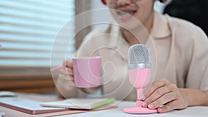 Cropped view of man sitting in front of microphone talking and recording podcast at home studio. Mass media, technology