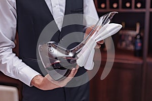 Cropped view man sommelier holding decanter with red wine