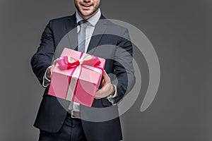 cropped view of man in suit holding gift box