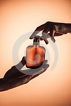 cropped view of man and woman holding one bottle of perfume,
