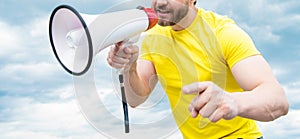 cropped view of man in yellow shirt shouting in loudspeaker on sky background