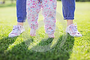 Cropped view of mother supporting baby daughter and helping her make first steps