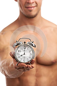 Cropped view of a muscular young man holding clock