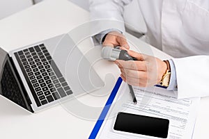 Cropped view of otolaryngologist holding otoscope