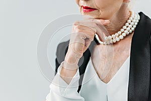 cropped view of pensive senior lady with pearl necklace,