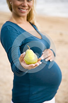 Cropped view of pregnant woman holding pear