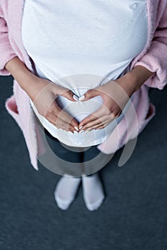 cropped view of pregnant woman making heart symbol with hands on her belly