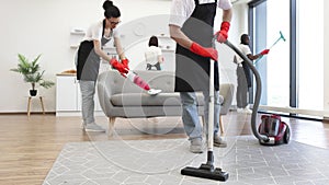 Cropped view of professional cleaner from cleaning service vacuums carpet.