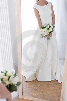 cropped view of reflection of bride in traditional dress with wedding bouquet