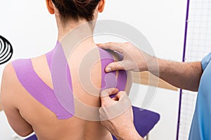 cropped view of rehabilitologist applying tape