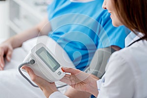 cropped view of smiling doctor measuring blood pressure of patient in hospital.