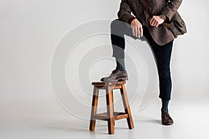 Cropped view of stylish mature man putting leg on chair while standing