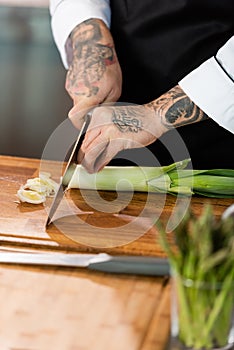 Cropped view of tattooed chef cutting