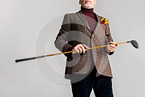 Cropped view of trendy mature man holding golf club and while standing isolated