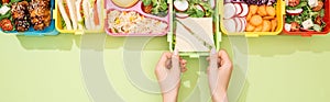 Cropped view of woman choosing lunch boxes with food.