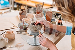 cropped view of woman decorating ceramic bowl in pottery