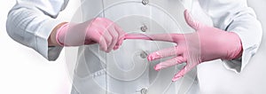 Cropped view of Woman Doctor in uniform putting on pink sterile gloves isolated on white background