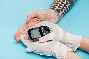 Cropped view of woman in gloves with glucometer