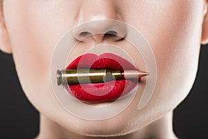 cropped view of woman holding bullet in red lips