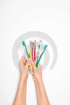 Cropped view of woman holding colorful toothbrushes in hands