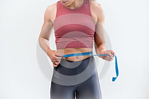 Cropped view of woman holding measuring tape along waistline isolated on white background