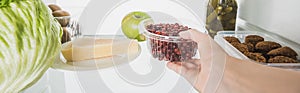 Cropped view of woman taking plastic tray with currant from fridge with food