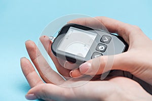 Cropped view of woman testing glucose level with glucometer