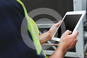 cropped view of worker in safety vest using digital tablet