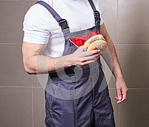 Cropped view of worker wearing uniform eating burger during lunch break