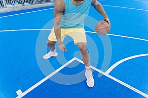 Cropped view of a young man on street basketball court dribbling with the ball