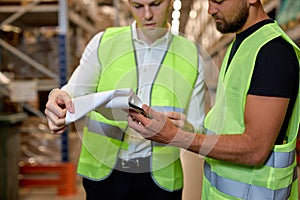 cropped warehouse managers in work wear organizing distribution in warehouse storage area.