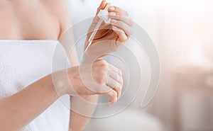 Cropped of woman applying serum on hand