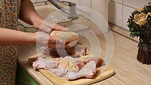 Cropped woman in bathrobe cook breaded chicken cutlets from raw chicken, smearing with breadcrumbs on cutting board