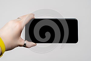 Cropped woman hand holding smartphone with blank screen horizontally on white background