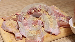 Cropped woman hand spicing, salting and adding breadcrumbs to marinated fresh pink chicken meat on wooden chopping board