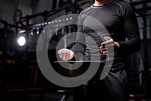 Cropped young athlete getting ready for weight lifting training, use talc