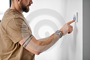 cropped young man using smart home system or activating heat system in cozy apartment