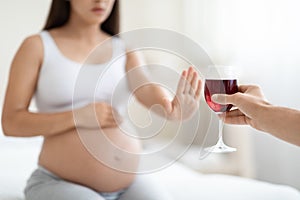 Cropped of young pregnant woman refuses to drink wine