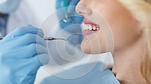 Cropped of young smiling woman and dentist hands with tools