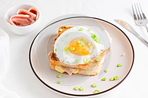 Croque madam sandwich with cheese, ham and egg on a plate on a light table. Hearty homemade breakfast